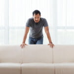 angry asian man standing couch leaning it looking camera 1