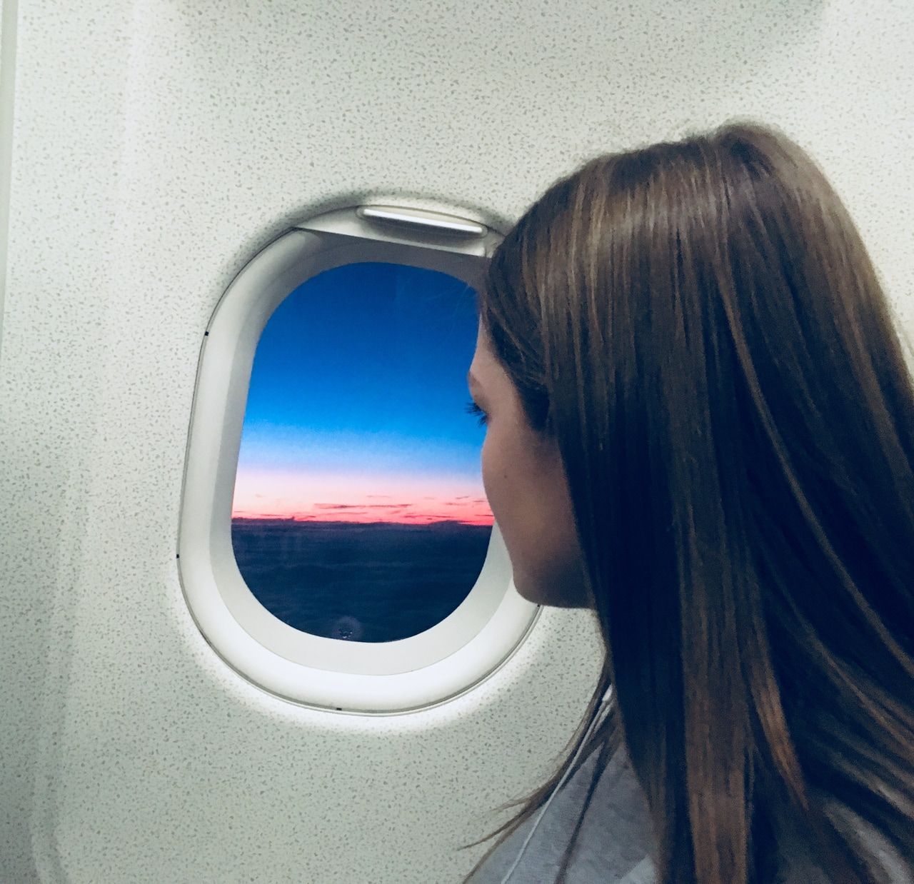 menina sentada no assento da janela no avião