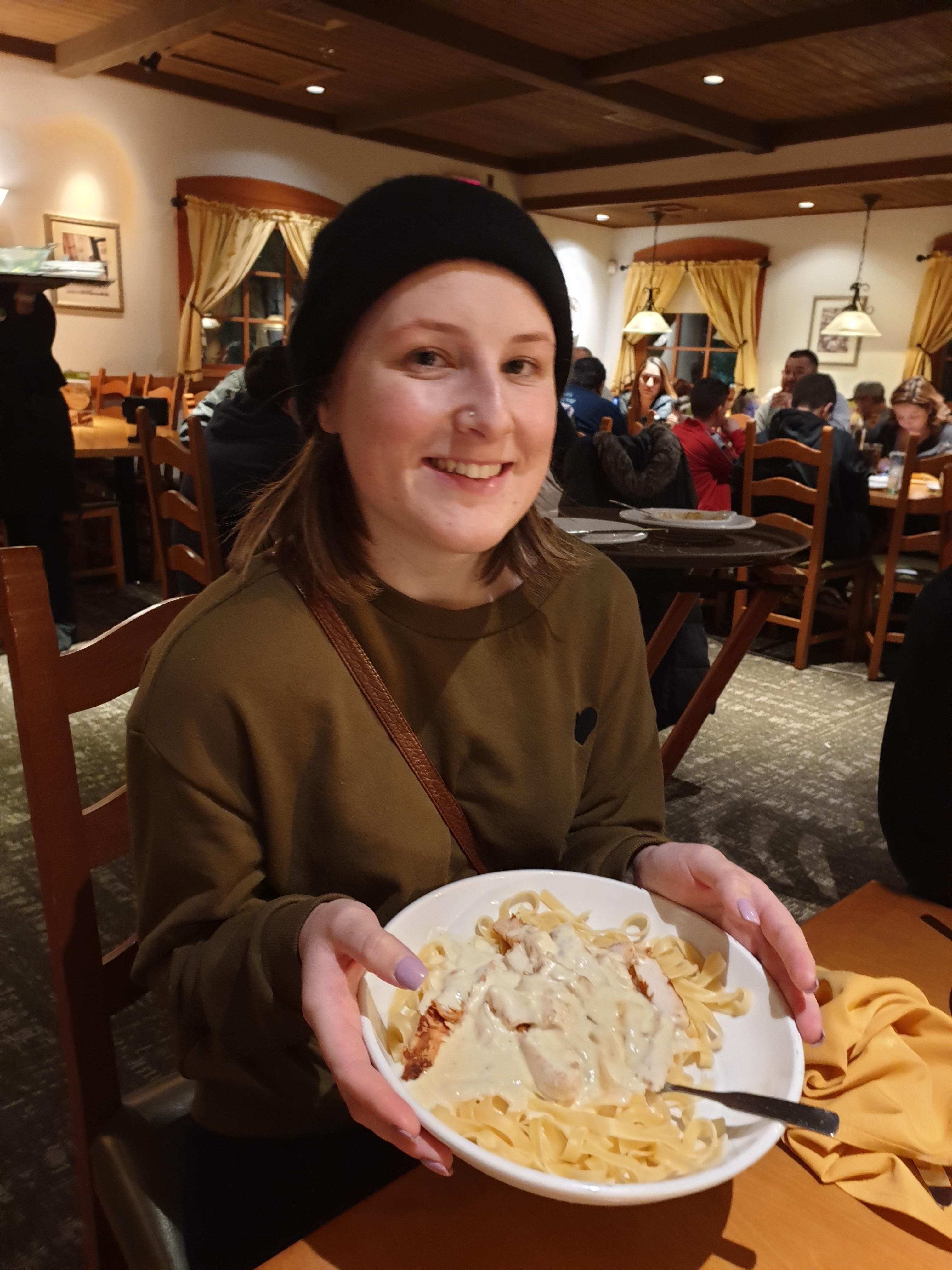 Pratos mais pedidos em restaurantes dos EUA 7 menina segurando prato de frango alfredo no restaurante olive garden