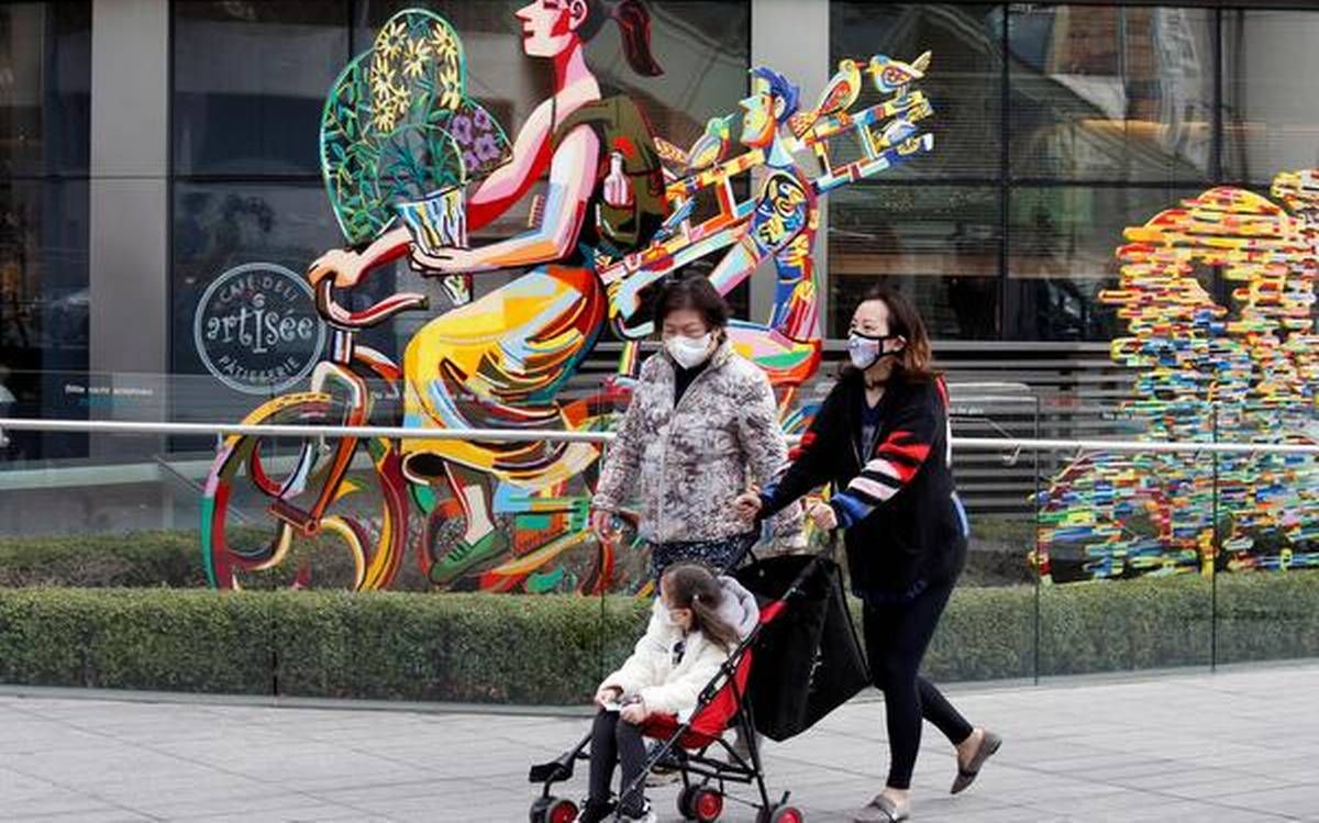 uma família usando uma máscara protetora dá um passeio lá fora