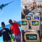 two people throw up the peace sign as a plane flies overhead, on board a caymen airways plane