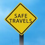 Yellow safe travel sign against blue sky