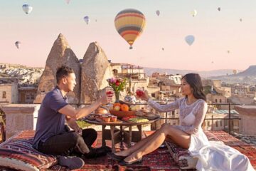 a couple has dinner at sunset while watching hot air balloons in Cappadocia, Turkey