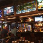 customers sit at the bar in a british pub