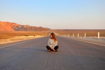 a girl sits in the middle of a road in peru