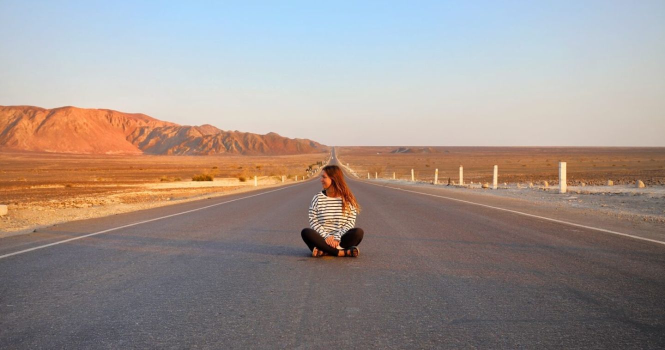 uma garota sentada no meio de uma estrada no peru