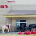 People with horses and a carriage at a McDonald's drive-thru