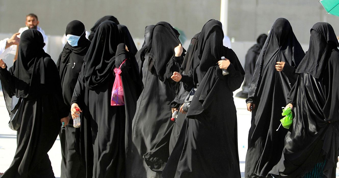 um grupo de mulheres na arábia saudita caminha pela rua com roupas tradicionais