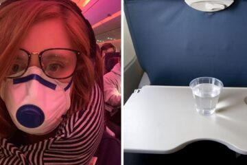 a girl wears a face mask on a plane, a cup of water on a plane tray