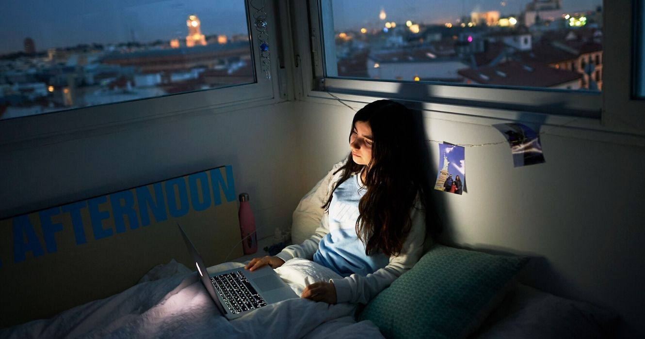 Tudo o que você precisa saber sobre viagens virtuais 1 uma garota se senta em seu laptop à noite na cidade