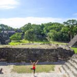a woman does yoga at the tikal ruins in guatemala
