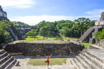 a woman does yoga at the tikal ruins in guatemala