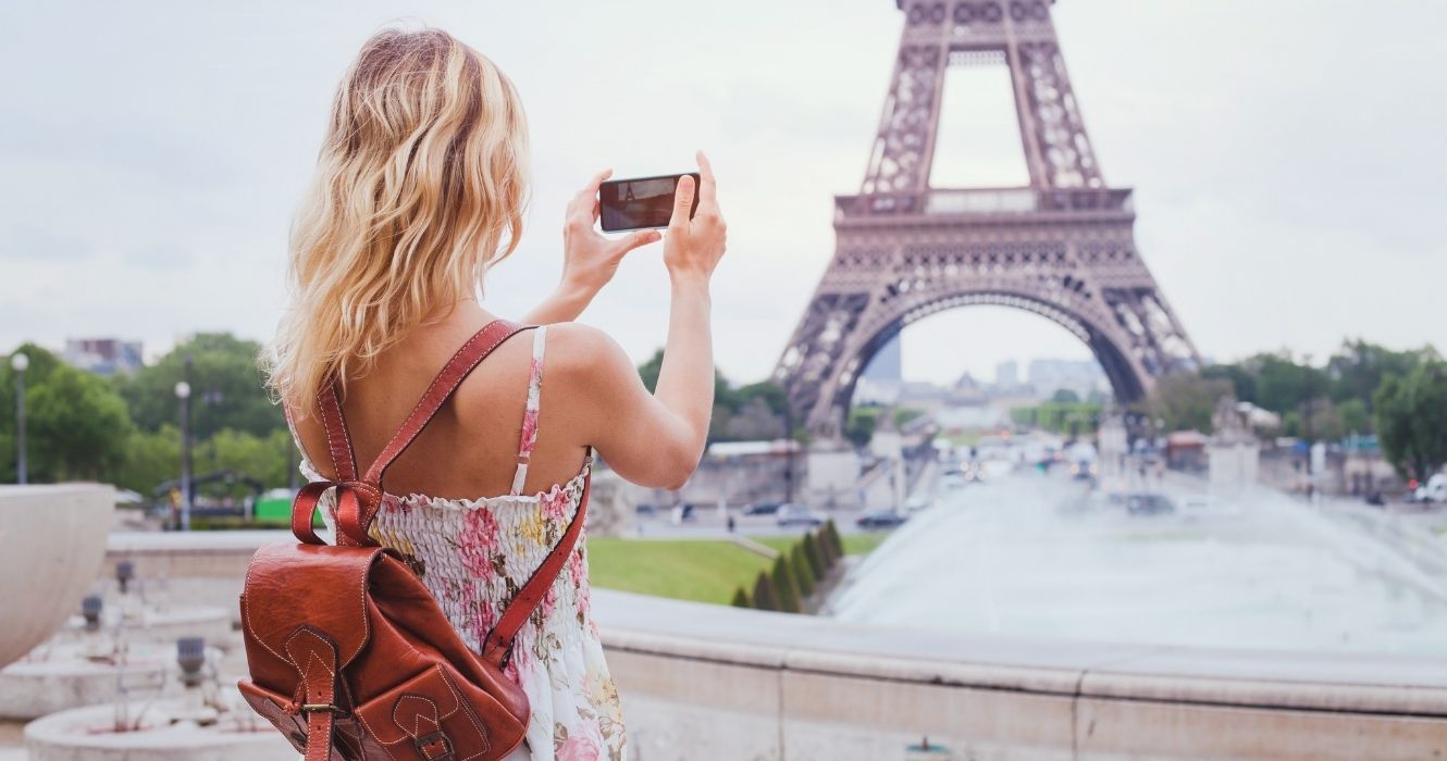 É essencial saber essas coisas antes de reservar férias na Europa agora 1 um viajante tirando uma foto da torre eiffel