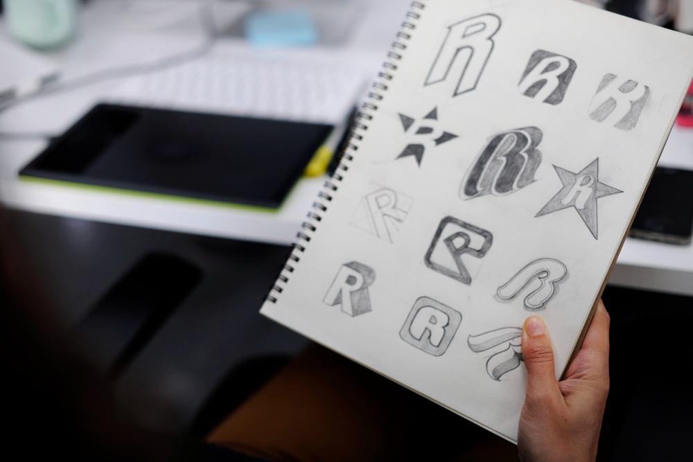 Logos e princípios básicos ao criar 1 hand holding notebook with drew brand logo creative design ideas